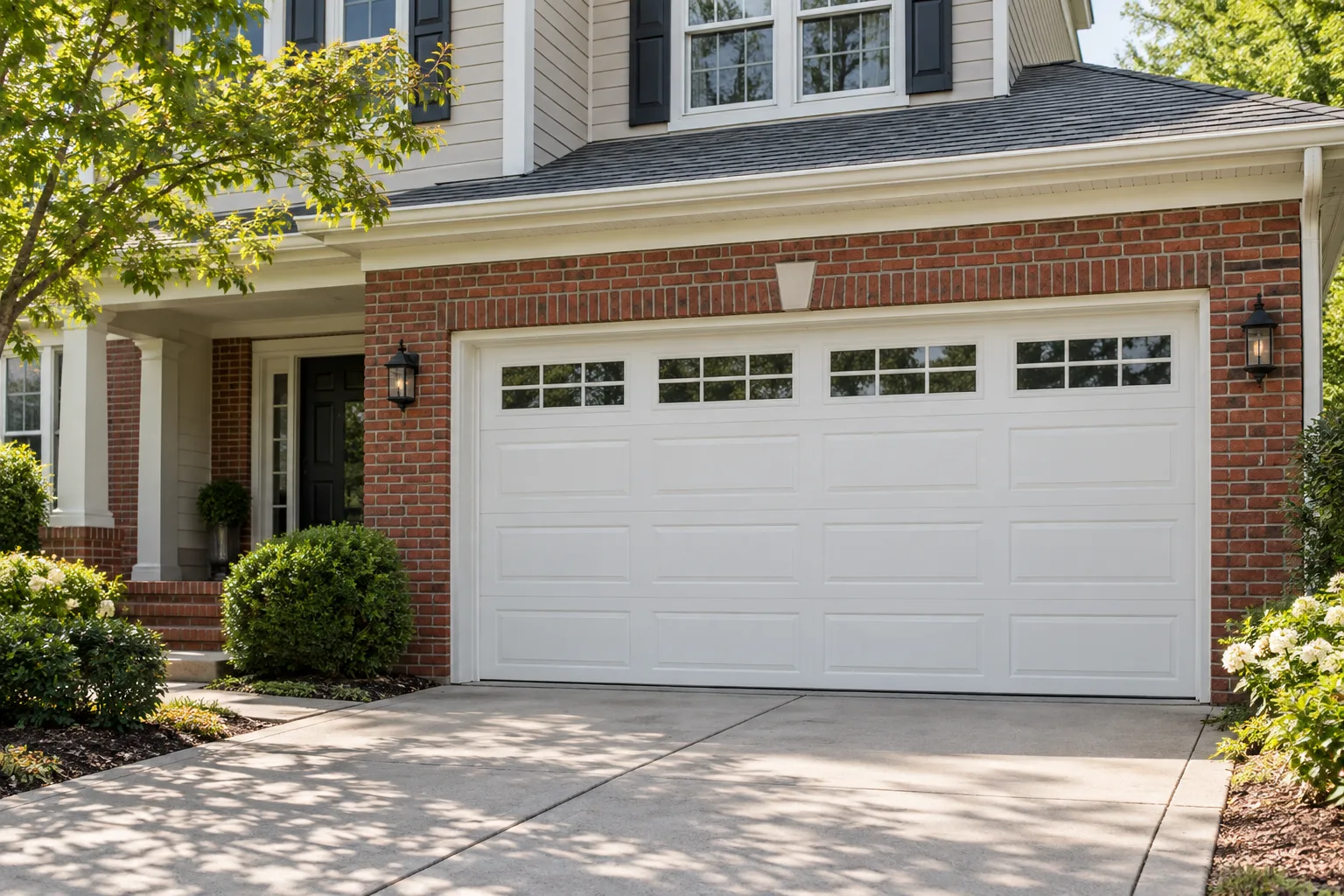 White sectional garage door on a brick and siding house.